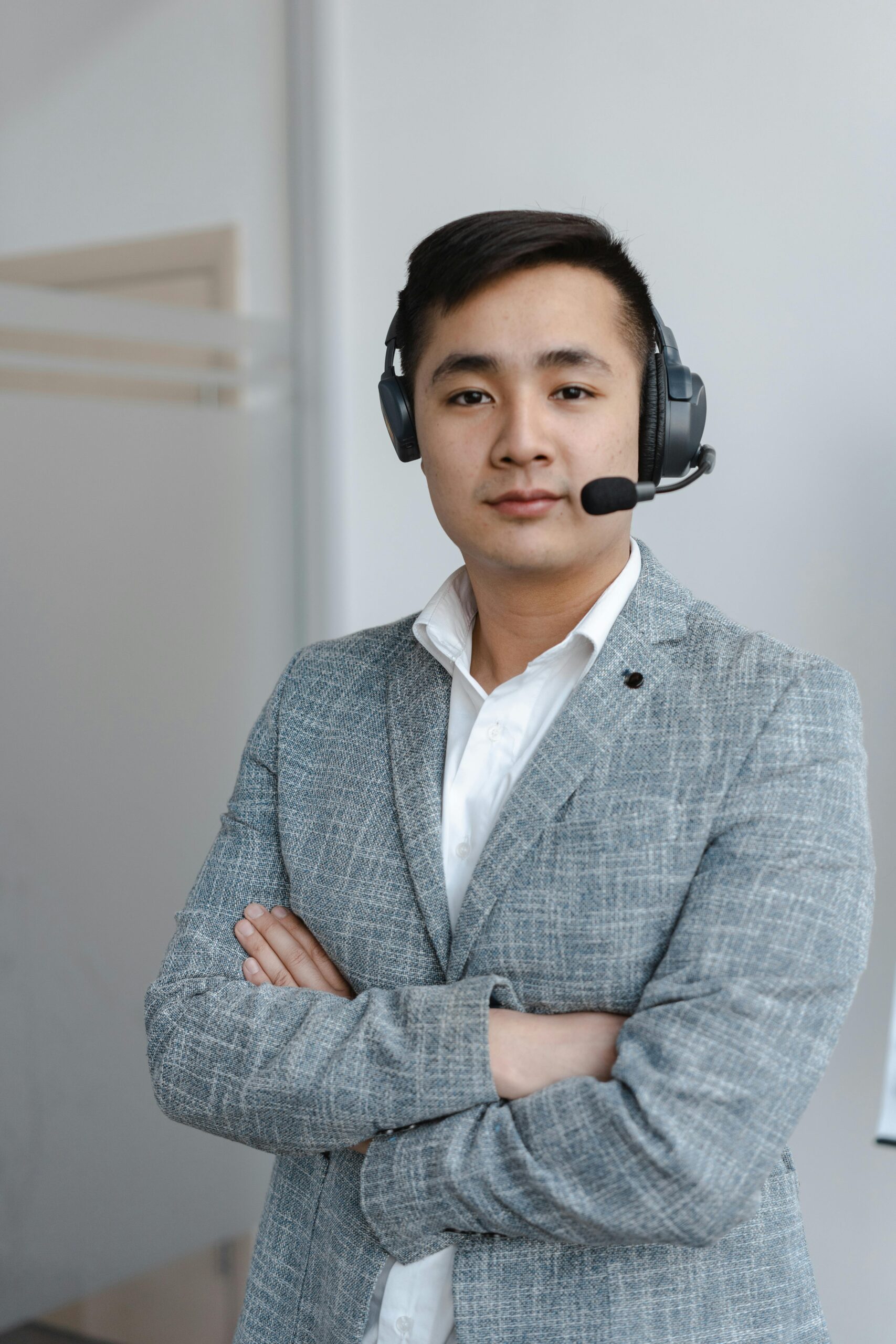 Asian male call center operator wearing a gray suit with a headset, providing customer service support.